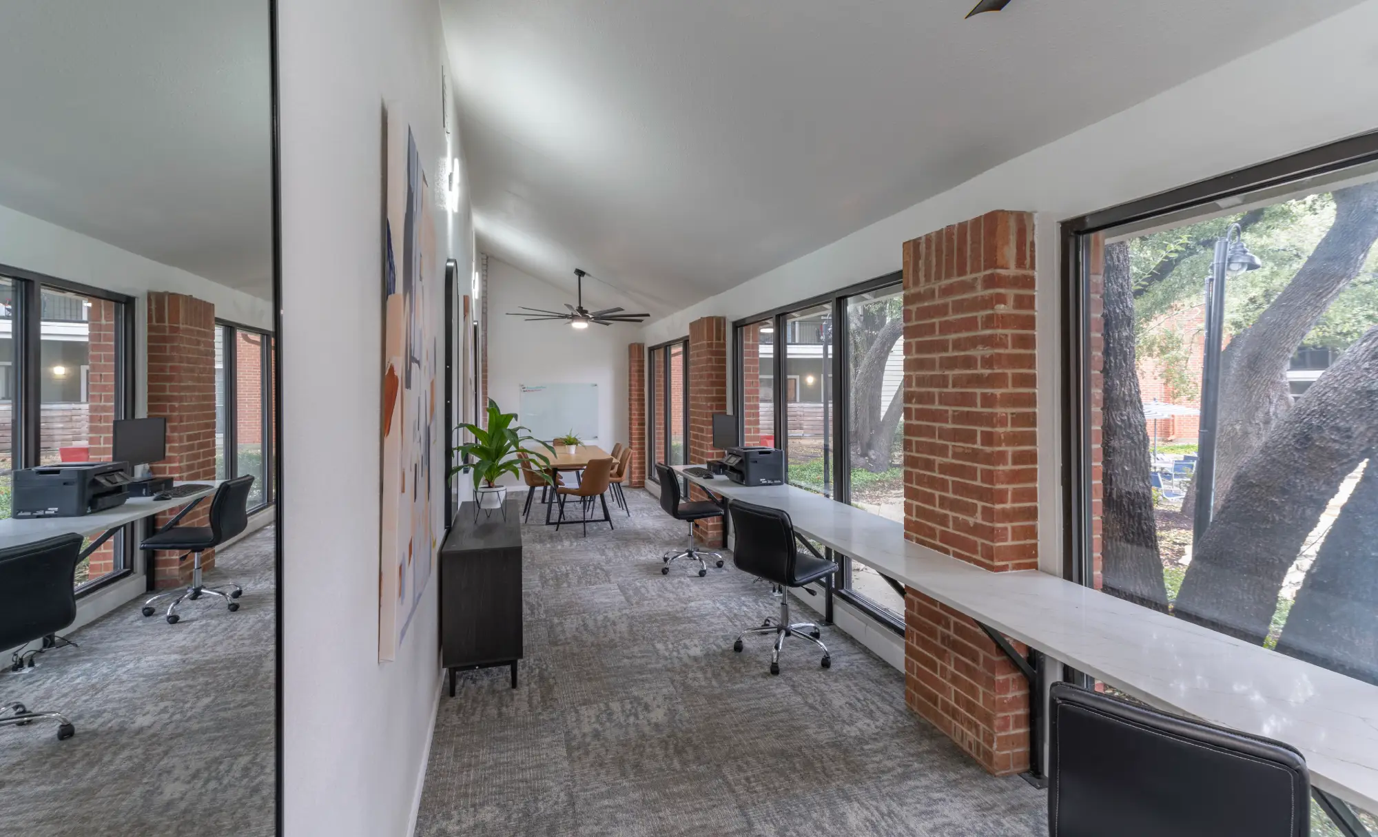 Apartment coworking space with desks, mirrored wall, and exposed brick columns