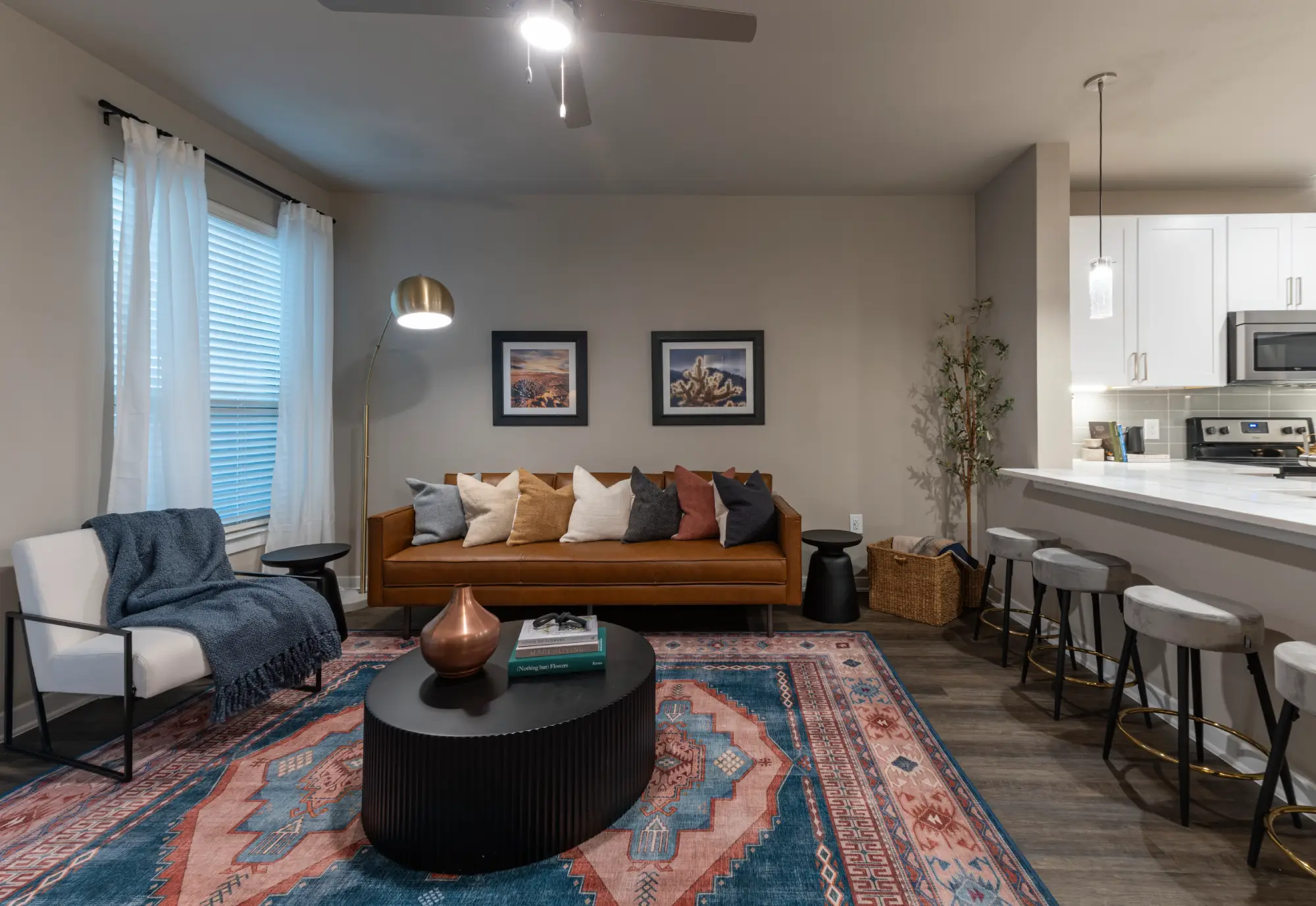 Apartment living room with cognac leather sofa, patterned rug, and kitchen bar seating