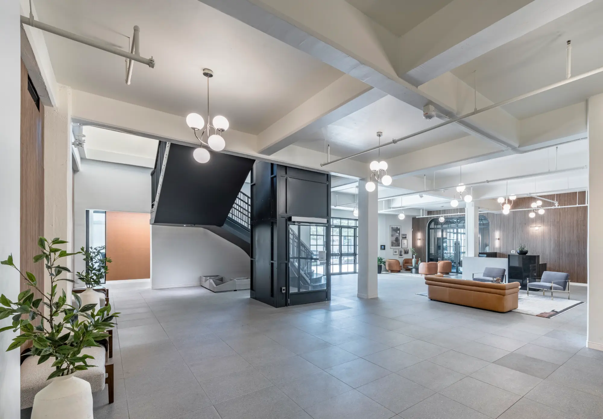 Tribute lobby with black steel staircase, exposed beams, and lounge seating area