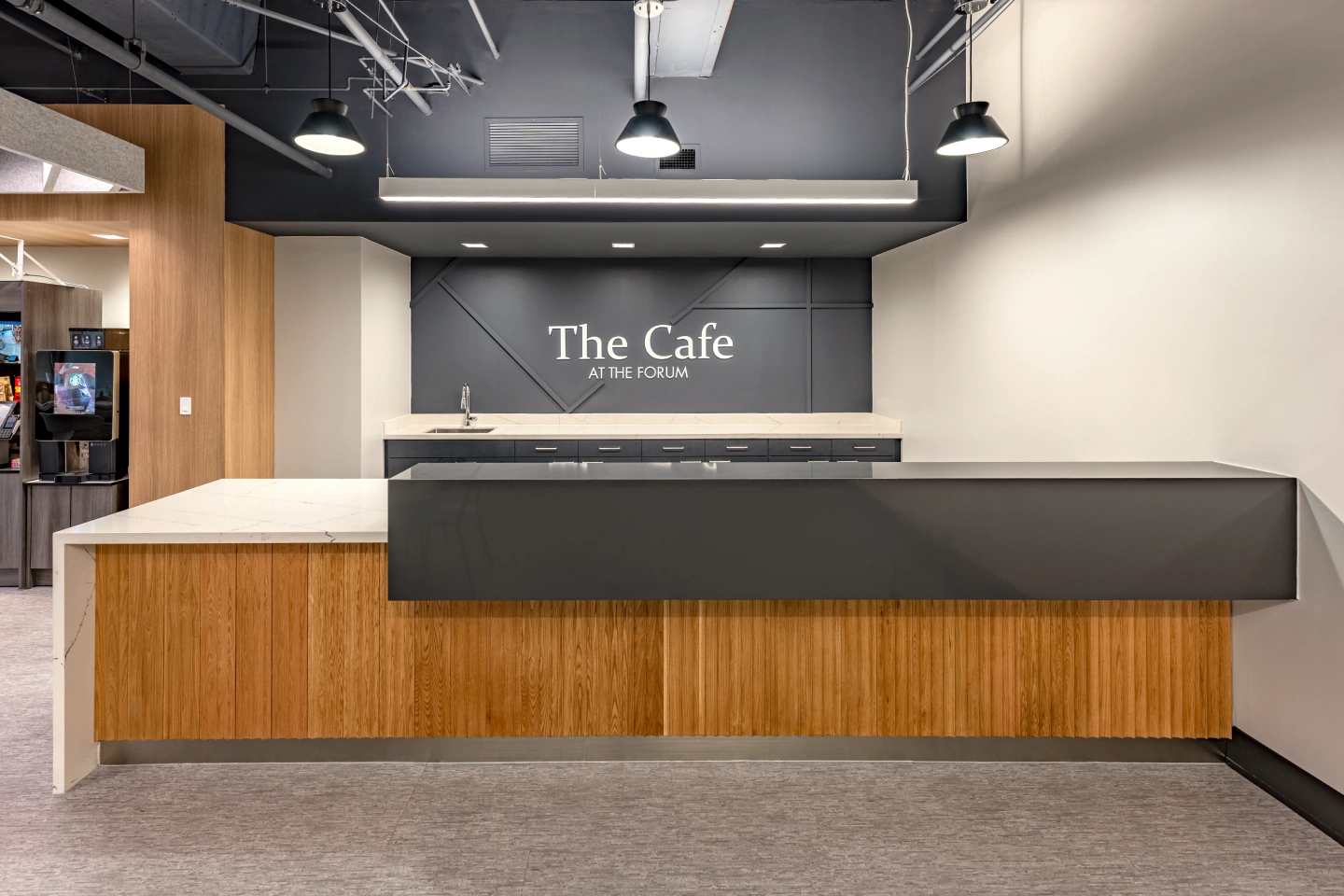 The Cafe at The Forum counter with wood slats, stone countertops, and industrial pendant lighting.