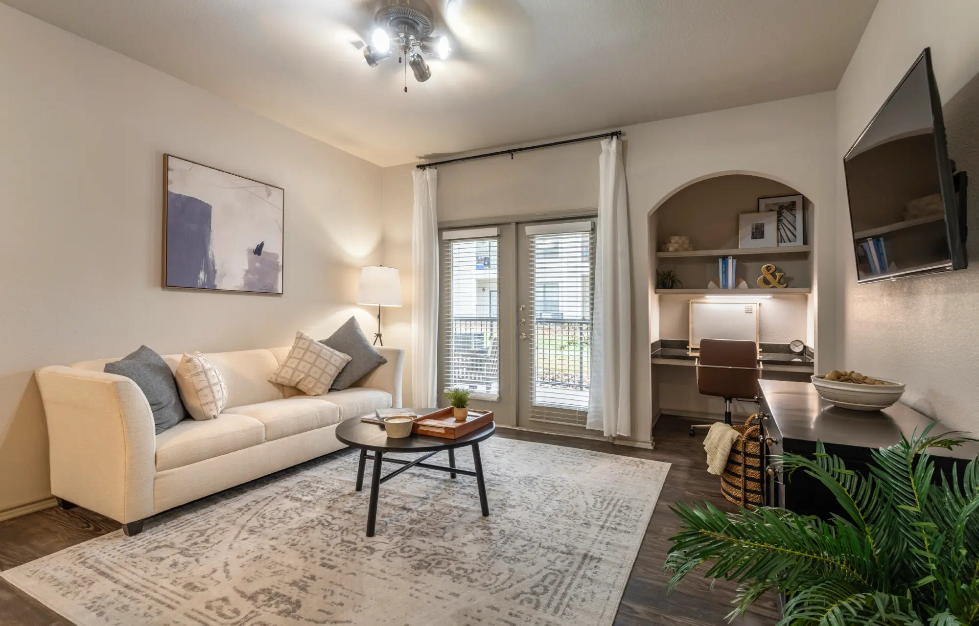 Apartment living room with cream sofa, built-in desk nook, and patio door